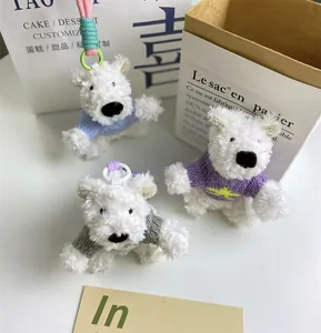 Trois adorables porte-clés chiens Westie en peluche avec pulls colorés sur fond blanc
