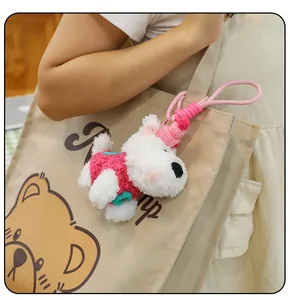 Cute white Westie plush dog keychain with pink knitted sweater hanging on a canvas tote bag