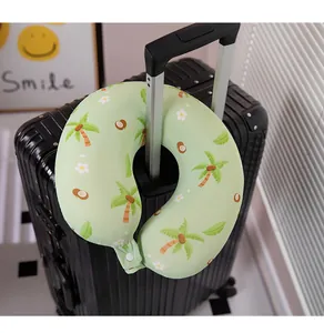 Almohada de cuello en U verde con palmeras montada en el asa de una maleta negra