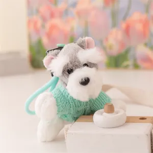 Primo piano di un simpatico portachiavi in peluche Schnauzer con un maglione verde