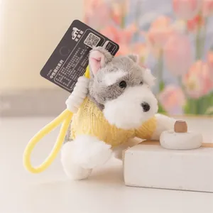 Dettaglio di un simpatico portachiavi a forma di cane Schnauzer in peluche con maglione giallo