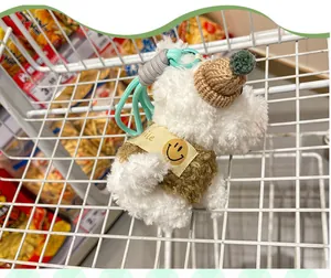 Close-up of a fluffy Westie dog plush keychain with a knitted hat and smile collar.