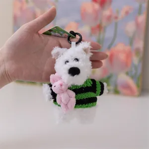 Dettaglio di un portachiavi in peluche con cane bianco che tiene un coniglietto rosa.