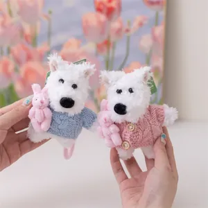 Dettaglio di portachiavi in peluche Westie con maglioni lavorati a maglia blu e rosa