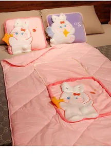 Close-up of cute rabbit plush pillow unfolded into a pink quilted summer blanket