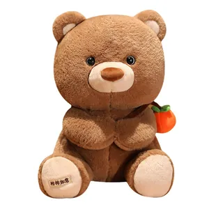 Adorable brown teddy bear plush toy with a small persimmon and a lucky foot patch