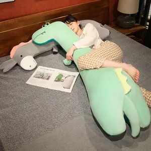 Largo cojín de peluche de dinosaurio verde en un acogedor escenario de dormitorio