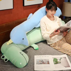 Modelo asiática apoyada en lindos cojines de peluche con forma de narval y dinosaurio