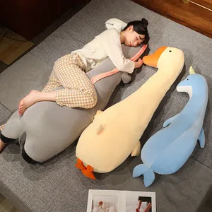 Modelo durmiendo con almohadas largas de felpa con forma de animales en una cama gris