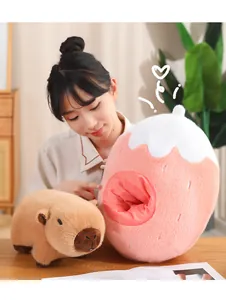 Modelo asiática mostrando un peluche de carpincho junto a un nido con forma de fresa