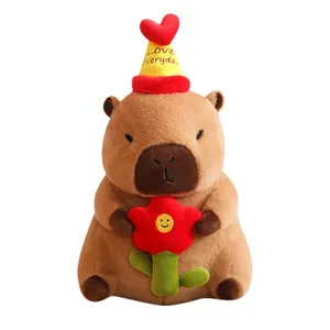 Peluche capybara mignonne avec un chapeau d'anniversaire jaune et une fleur rouge