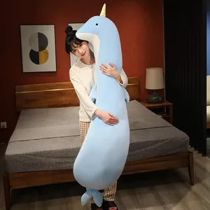 Gran almohada larga de peluche de narval azul para dormir de lado en un dormitorio