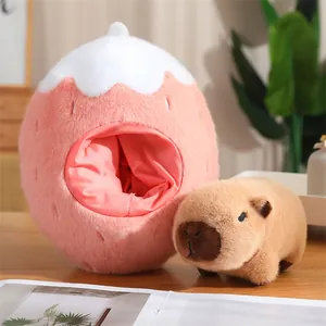 Detalle de peluche de Capibara marrón junto a un nido de peluche de fresa rosa