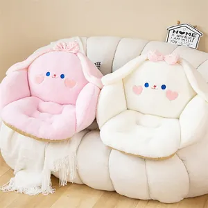 Par de adorables cojines de asiento de felpa de conejo en rosa y blanco en un sofá