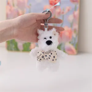 Macro vista di un portachiavi a forma di cucciolo di peluche bianco con fiocco