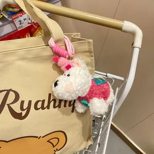 Cute plush West Highland White Terrier puppy keychain charm hanging on a canvas tote bag.
