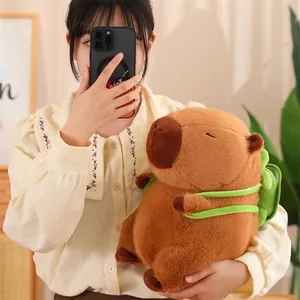 Jeune fille tenant une peluche Capybara marron mignonne avec accessoire sac à dos vert.