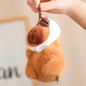 Détail d'un mignon porte-clés en peluche capybara marron avec capuche blanche et clochette