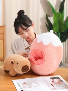 Vista detallada de un peluche de carpincho junto a su casita en forma de fresa rosa