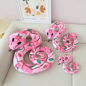 Close-up of pink cherry blossom patterned snake plush toys in three sizes on a sofa