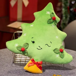 Vue détaillée d'un coussin en peluche sapin de Noël avec visage et houx décoratif