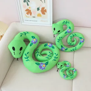 Detail of three green plush snakes with flower patterns in different sizes on a sofa.