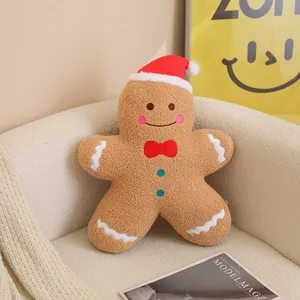 Gros plan d'un coussin en peluche bonhomme de pain d'épice avec un bonnet de Noël rouge.