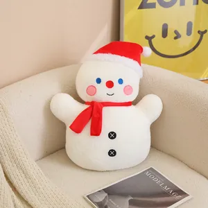 Coussin bonhomme de neige de Noël en peluche avec écharpe rouge sur fauteuil blanc