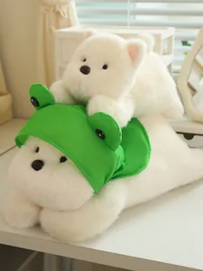 Macro view of white Westie plush dog wearing a cute green frog hat on a desk