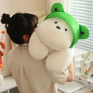 Soft white West Highland Terrier plush toy with a green frog hat being held by a model