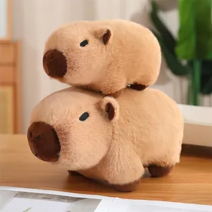 Pila de dos adorables peluches de Capibara marrones sobre una mesa de madera