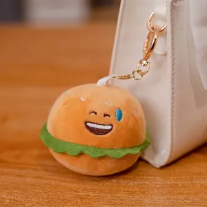 Lindo llavero de hamburguesa de peluche con expresión graciosa en un bolso blanco