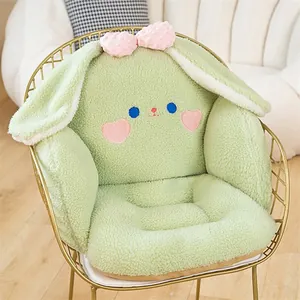 Lindo cojín de peluche de conejo verde con respaldo sobre una silla dorada.