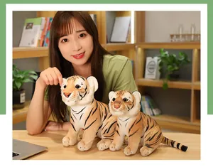 Dos peluches de tigre amarillo realistas en una mesa de madera con una modelo asiática.