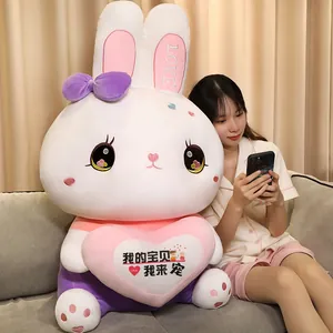 Close-up of a large white rabbit plush toy with a pink heart being held by a girl on a sofa
