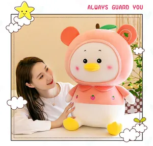 Close-up of a cute fruit-themed duck plush toy being held by a smiling person in a soft light
