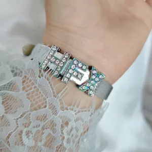 Primo piano di ciondoli alfabetici in strass da 10 mm su un cinturino grigio