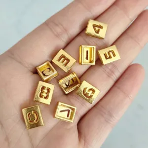Close-up detail of 8mm matte gold alloy hollow number charms for DIY jewelry and wristbands