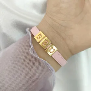 Close-up detail of 8mm matte gold hollowed 520 number charms on a pink leather wristband.