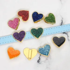 Close-up of colorful glitter heart charms displayed on a light blue leather strap