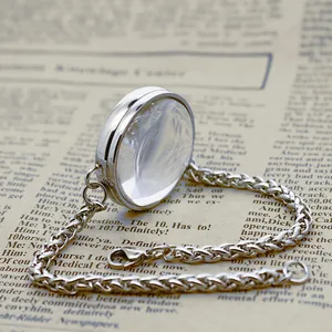 Macro view of a curved glass floating locket on a stainless steel wheat chain bracelet.