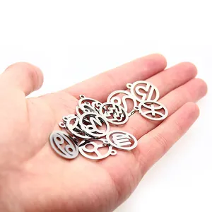 Close-up view of multiple DIY stainless steel zodiac constellation charms held in a palm