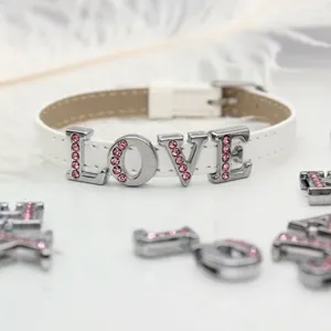 Close-up of 8mm pink rhinestone LOVE letters sliding onto a white leather bracelet strap