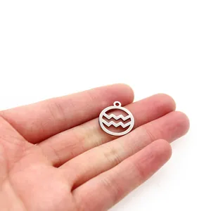 Close-up view of a stainless steel Aquarius zodiac sign pendant held in hand for scale