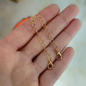 Detalle de una cadena dorada con dos cierres de langosta para accesorios de bolsos.