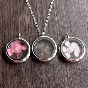 Detail view of 30mm stainless steel round glass lockets with dried flowers and seeds