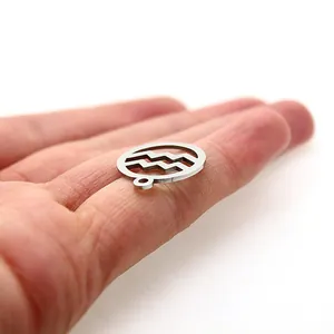 Detailed view of polished stainless steel Aquarius zodiac charm held on a finger
