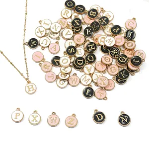 Variedad de dijes de letras del alfabeto en esmalte de colores en negro, blanco y rosa.