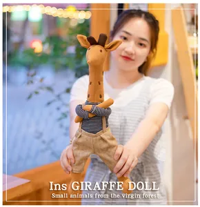 Close-up of a cute giraffe plush doll wearing a striped shirt and tiny overalls