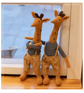 Detail of two cute stuffed giraffe toys wearing striped shirts and linen overalls